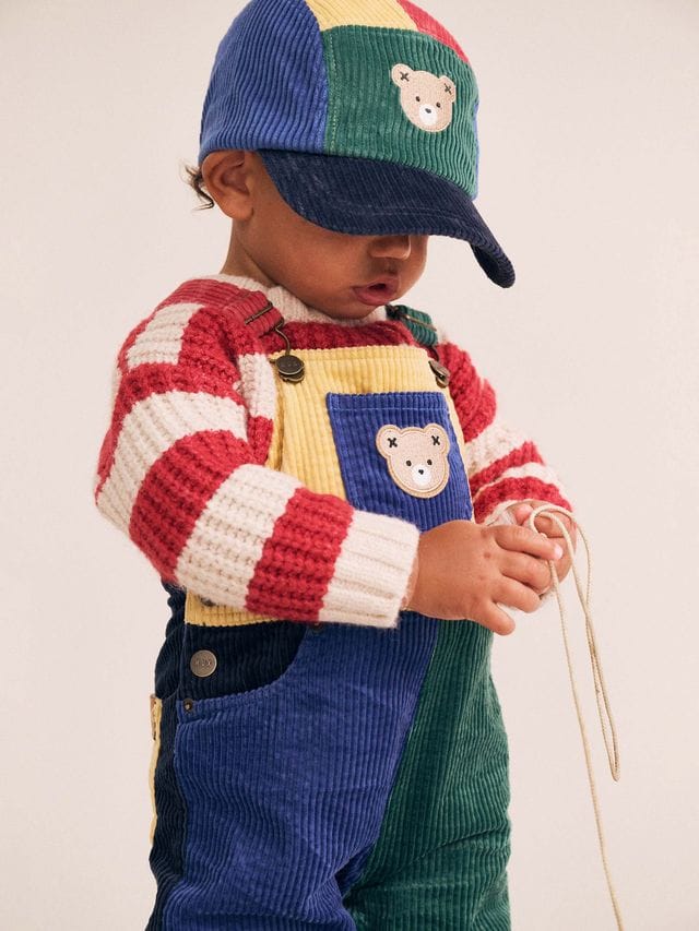 Huxbaby boys colour block cord overalls showing vibrant fabric with adjustable straps and front pockets on a white background.
