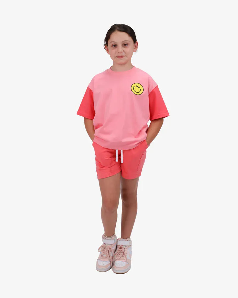 Coral girls' top from The Girl Club with happy icon print, featuring a casual and colorful design for young girls.